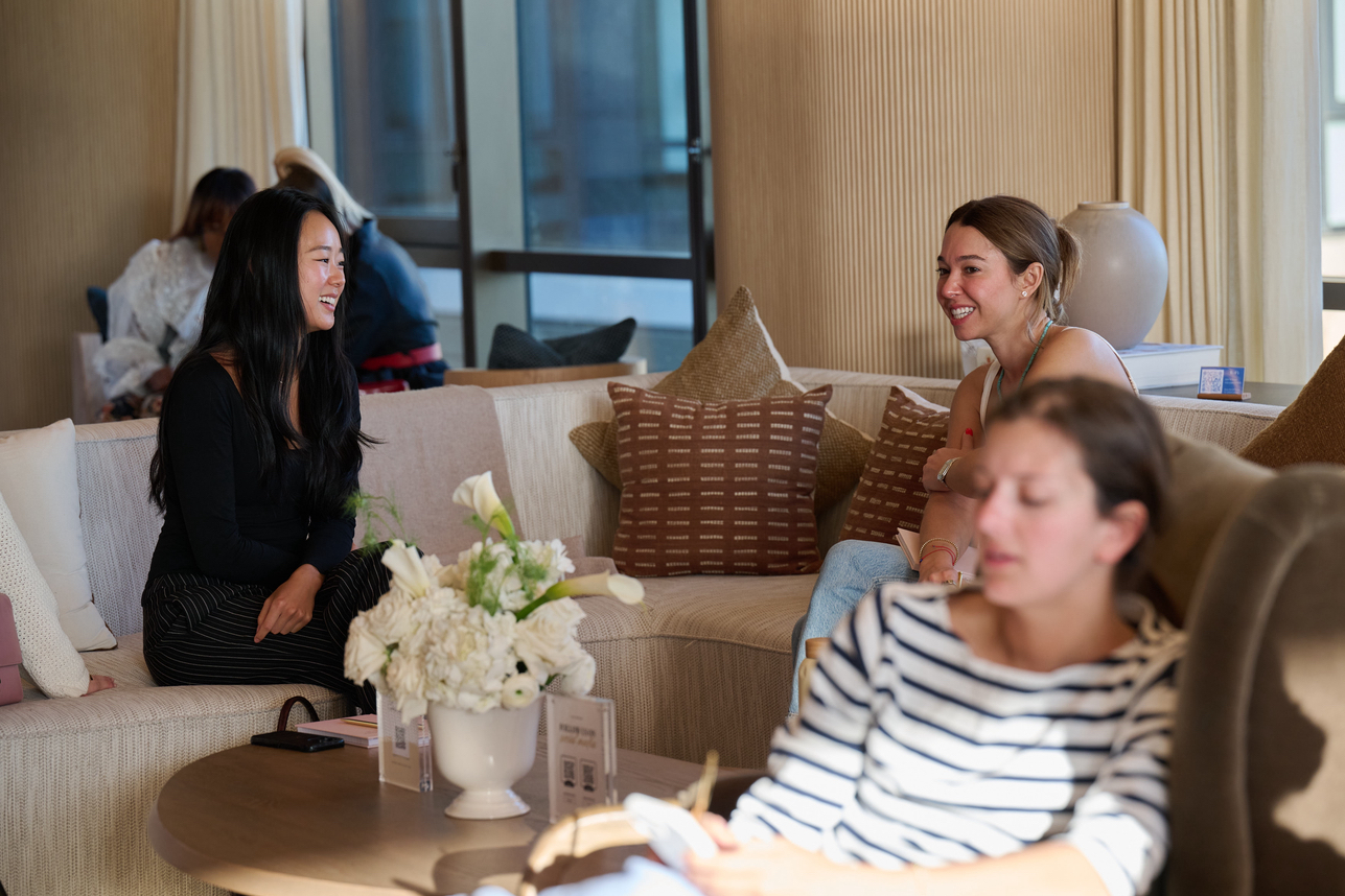 Attendees laughing and connecting on a couch with white floral arrangement