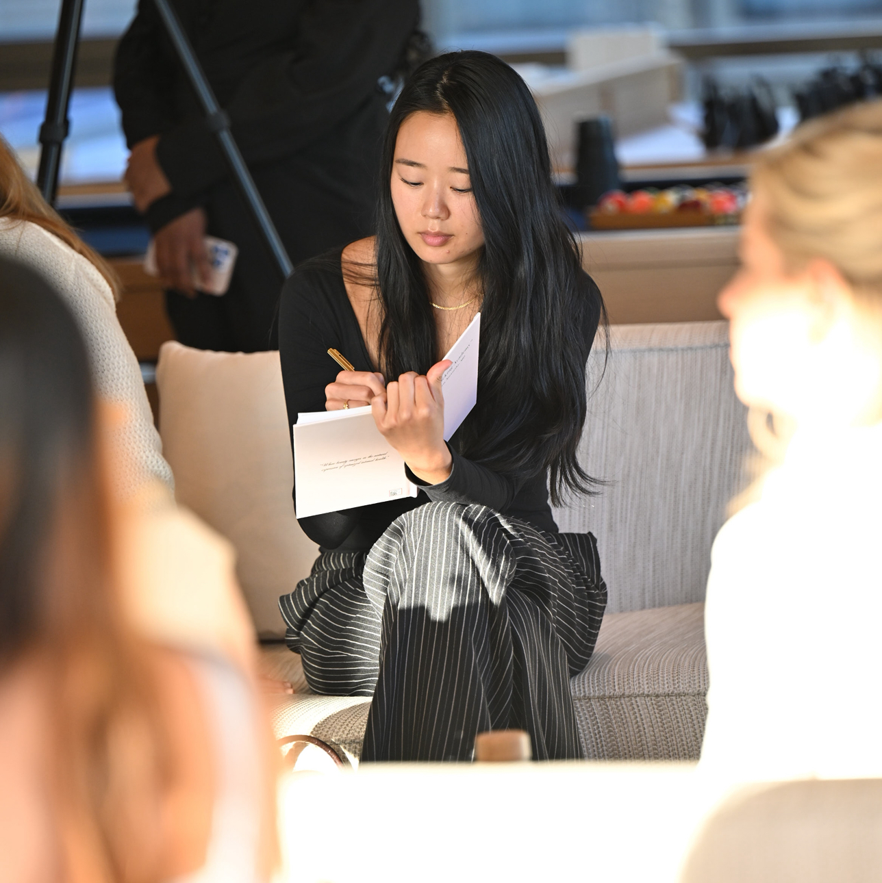 Attendee taking notes with a gold pen during the masterclass