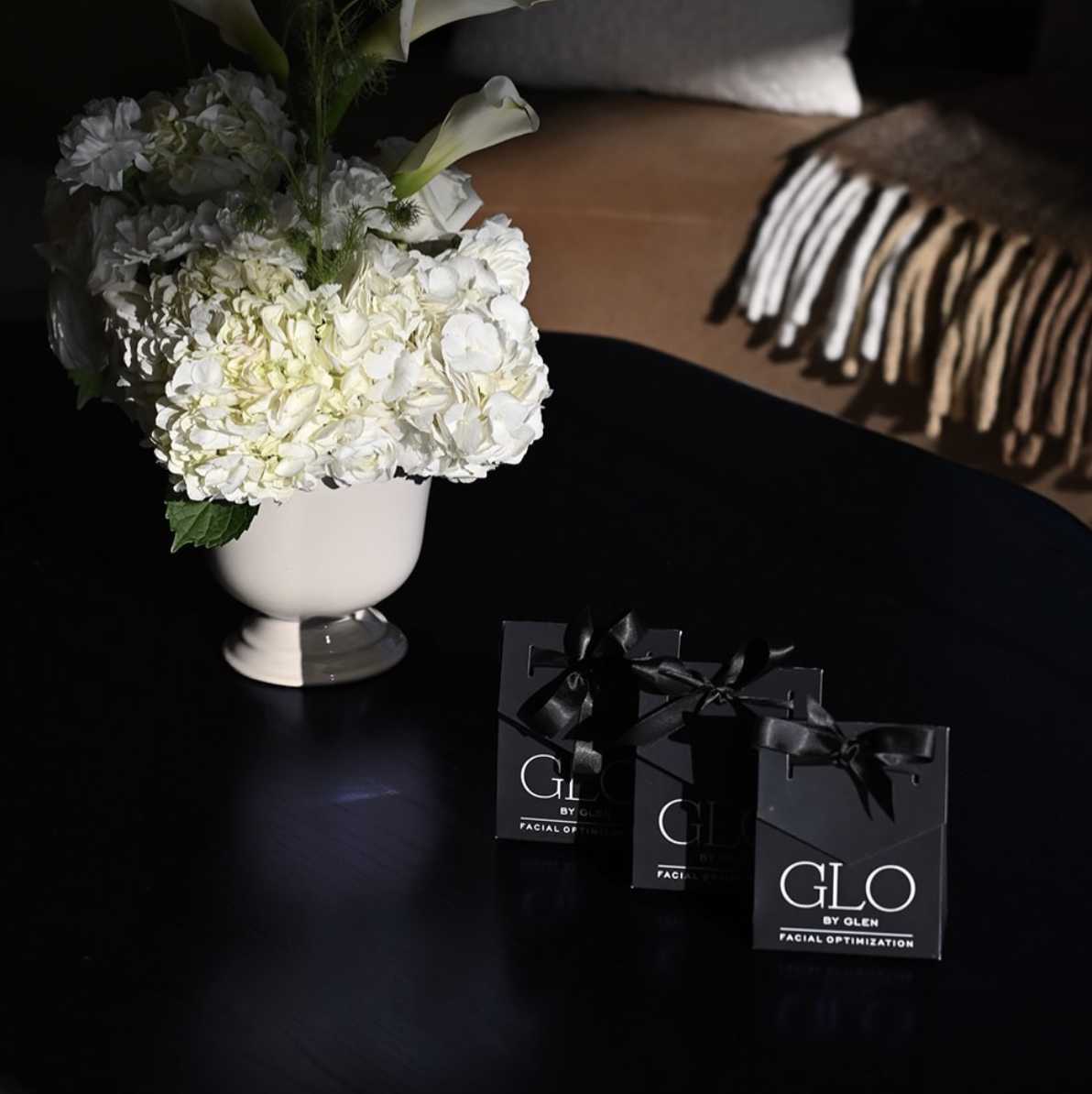 GLO by Glen gift boxes with white hydrangeas arranged on a dark table